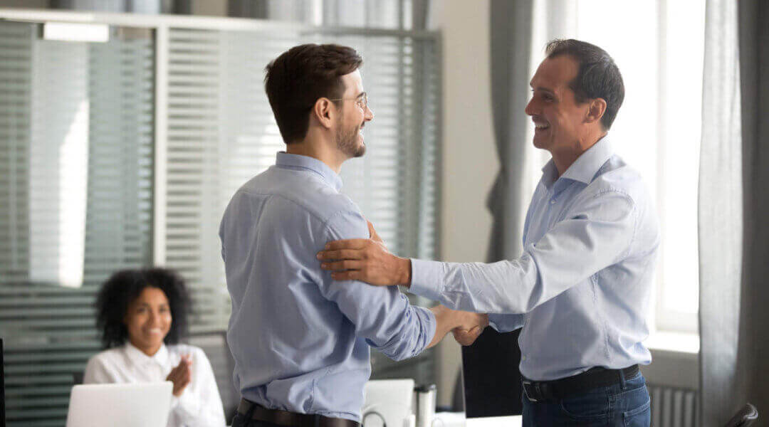 Smiling middle-aged ceo shaking hands with worker congratulating on bonus