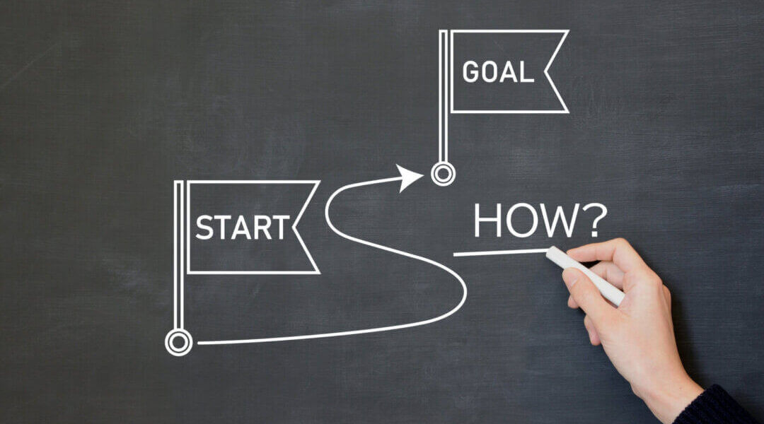 on chalk board, line connecting a flag that says "start" and another that says "goal" with the word "how" underlined between them, setting route from start to goal