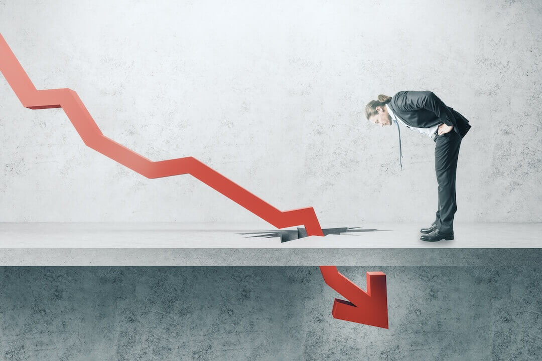 Businessman looking down at falling red arrow breaking through concrete ground.