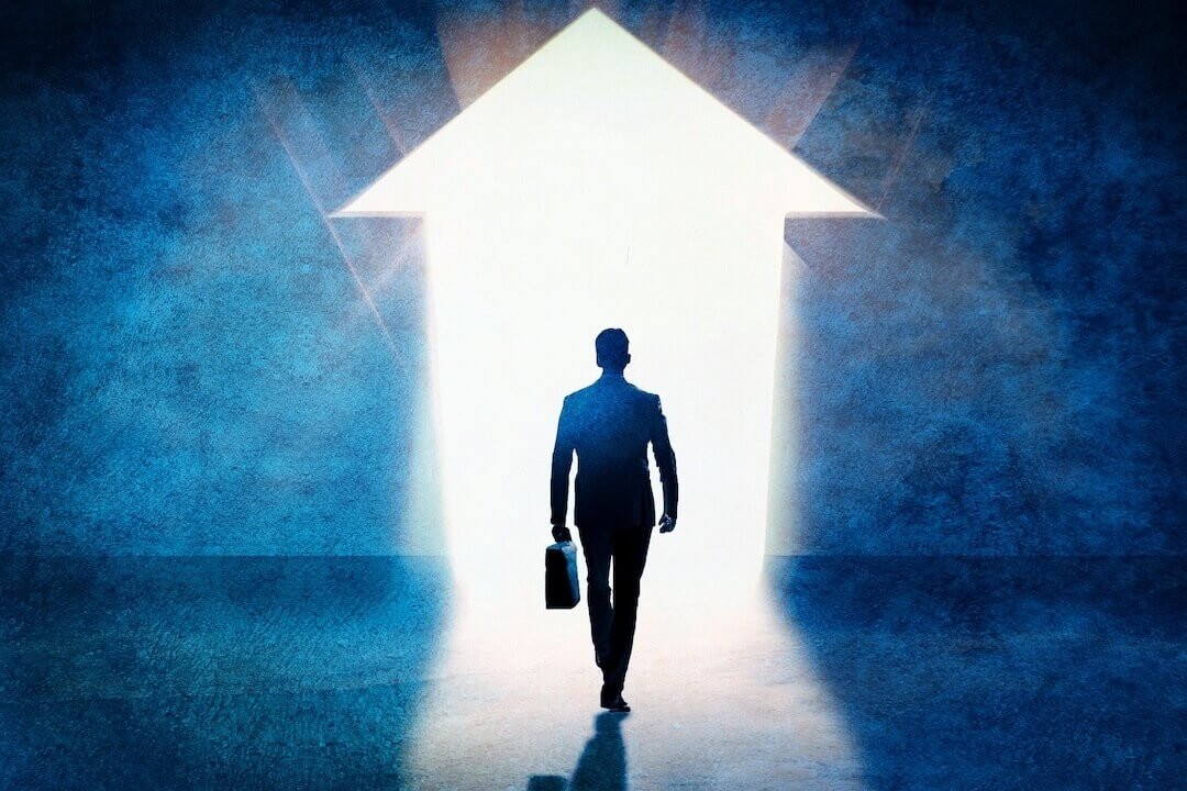 Business success concept. Businessman silhouette exiting in the direction of the bright arrow on the wall.