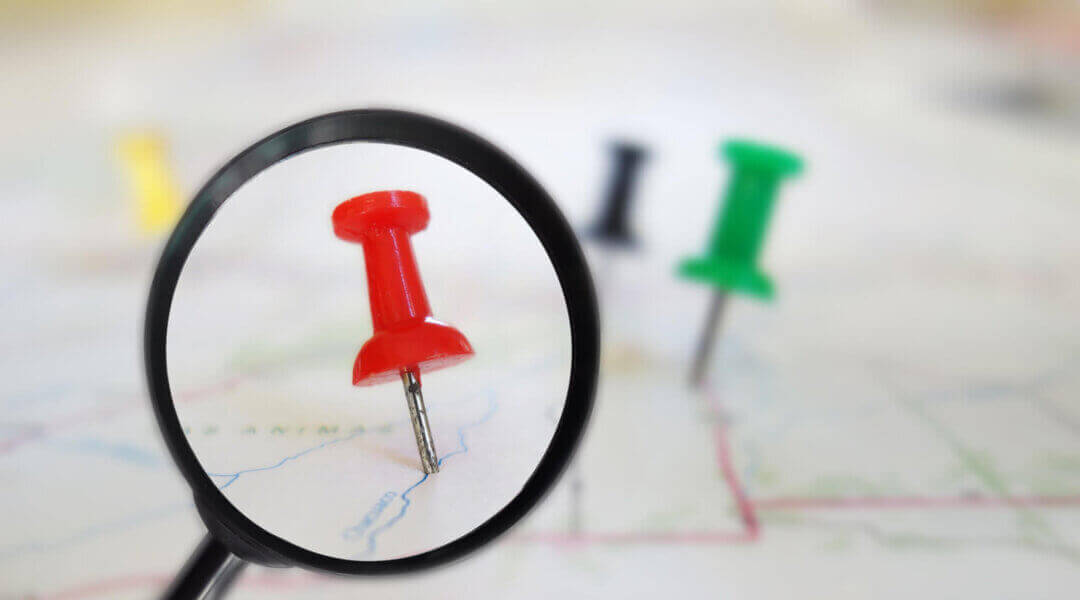 Magnifying glass closeup of push pin tacks in a map
