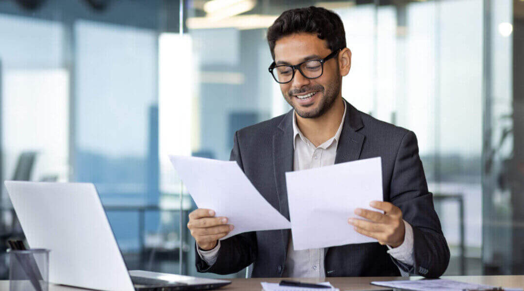 Successful mature experienced financier smiling satisfied with results of financial achievement, reviewing contracts, invoices and statements with accounts, businessman in suit.