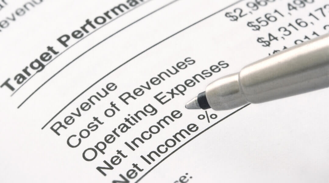 A pen pointing to line items on a business profit & loss report, including revenue, cost of revenues, and operating expenses.